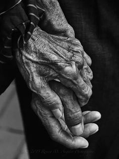 an old woman holding the hand of a younger person's hand in black and white