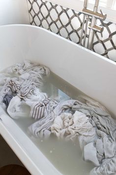 a bath tub filled with lots of dirty clothes