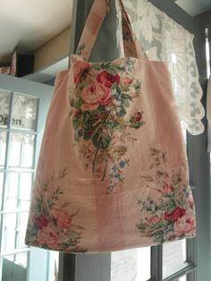 a pink bag hanging from the side of a window with flowers on it and lace