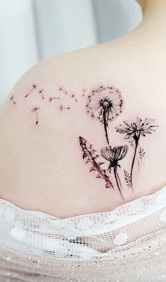 a woman's stomach with a dandelion tattoo on her back and side