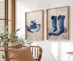 two framed pictures hang on the wall above a chair in front of a potted plant