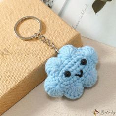 a blue crocheted keychain with a smiley face on it sitting next to a book