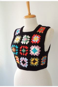 a white mannequin wearing a black sweater with multicolored flowers on it