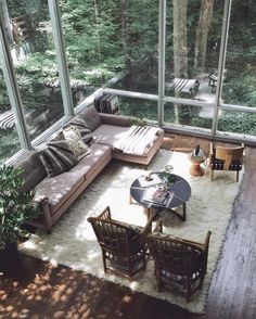 a living room filled with lots of furniture and large glass windows over the top of it