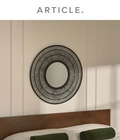 a bed sitting under a round mirror next to a wooden headboard and foot board