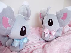 two stuffed animals sitting on top of a bed next to each other in pink sheets