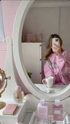 a woman taking a selfie in front of a mirror with pink accessories on it