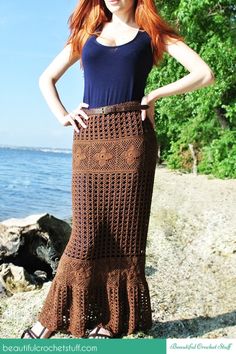 a woman wearing a long crochet skirt by the water with her hands on her hips