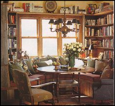 a living room filled with lots of furniture and bookshelves next to a window