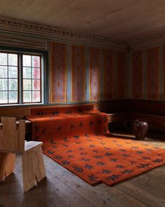 a living room with wood paneling and orange rug on the floor in front of two windows