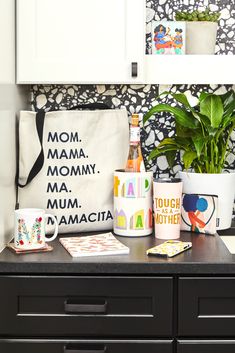 a black dresser topped with lots of clutter next to a potted green plant