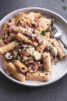 a white bowl filled with pasta covered in meat and cheese, garnished with parsley