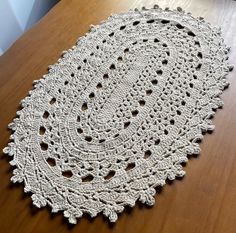 a crocheted doily sits on a wooden table, ready to be used as a placemat