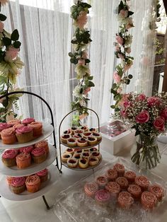 a table topped with cupcakes and cakes next to a vase filled with flowers