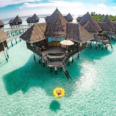 an aerial view of some huts in the water with a raft floating on it's side