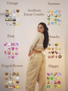 a woman is standing in front of a wall with many different emojs on it