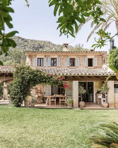 the house is surrounded by greenery and palm trees, with an outdoor dining area