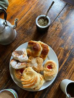 a plate full of pastries on a wooden table next to two cups of coffee