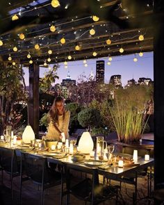 an outdoor dining area with lights strung from the ceiling and tables set up for dinner