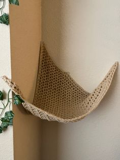 there is a small hammock hanging on the wall next to a potted plant