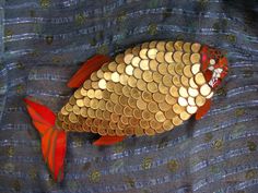 a fish made out of gold coins sitting on top of a blue blanket with red leaves