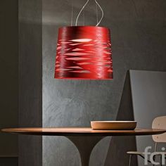 a red lamp hanging over a table with a bowl on the table next to it