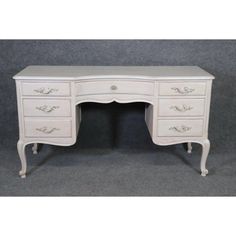 an antique white desk with drawers