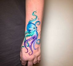 an octopus tattoo on the left wrist and right hand is painted with watercolors