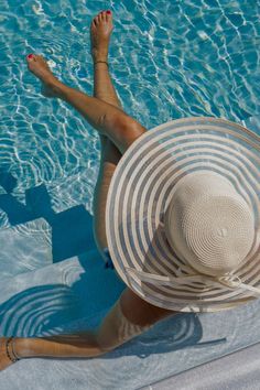 A woman sitting in a shallow pool with a big sunhat on in our resort capsule wardrobe. Airport Outfit Summer, Chic Capsule Wardrobe