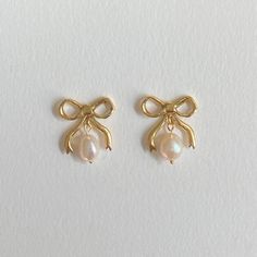 Decorate yourself with these Brass Bow beauties with two freshwater pearl drops with a shimmery golden 18CT Gold Plating. Inspired by a love of Victorian bygone jewels, these earrings are a playful nod towards popular motifs used, it's all about the dangle, brining a little glamour to your ears to be enjoyed on any occasion. .All posts are made from sterling silver and coated in 18CT Gold to protect sensitive ears  All pieces are handmade to order please allow 2-3 weeks for delivery. Your earrings will arrive housed in an embossed gift box. Bows available in Sterling Silver option.  Material Composition: Brass/18CT Gold Plating Sterling Silver 925 Freshwater Pearls Earrings With Pearls, Smink Inspiration, Preppy Jewelry, Jewelry Accessories Ideas, Dope Jewelry, Jewelry Lookbook, Jewelry Essentials, Classy Jewelry, Bow Earrings