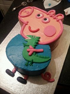 a cake that looks like peppa the pig holding a crocodile