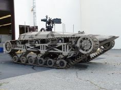 an army tank is parked in front of a building with a camera on it's side