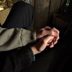 a person sitting down holding their hands together