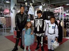 two children and an adult are posing for a picture in front of costumes on mannequins