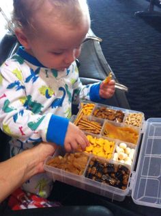 a toddler is eating food from a plastic container