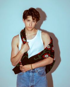 a young man in jeans and a tank top is posing for the camera with his hand on his hip