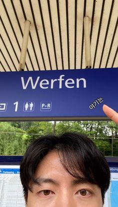 a man holding his hand up in front of a blue sign that says werfen