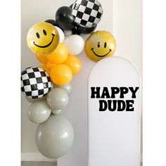 some balloons that say happy dude next to a sign with smiley faces and checkered balloons