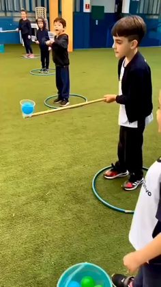 several children are practicing their skills in an indoor area with green grass and blue walls