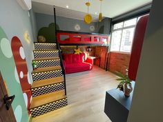 a room with bunk beds, stairs and a red couch in the middle of it