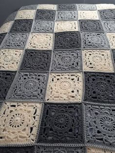 a crocheted afghan is shown on a bed with black and white squares in the middle