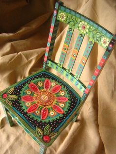 a colorful chair sitting on top of a bed next to a sheet covered tablecloth