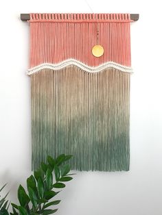 the wall hanging is decorated with fringes and a gold disc on it's center