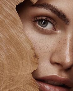 a woman with freckles on her face looking through a piece of wood