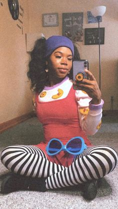 a woman sitting on the floor taking a selfie with her cell phone and wearing striped tights