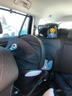 an infant seat in the back of a car with a stuffed animal on it's head