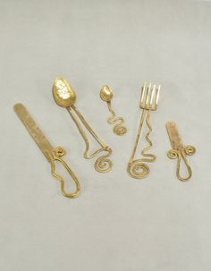 five golden utensils and two spoons on a white surface