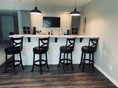 three bar stools at the end of a counter in a room with hardwood floors