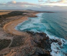 an aerial view of the beach and ocean with waves crashing on it's shore