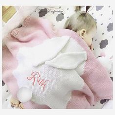 a baby doll wrapped in a pink and white blanket with an embroidered name on it